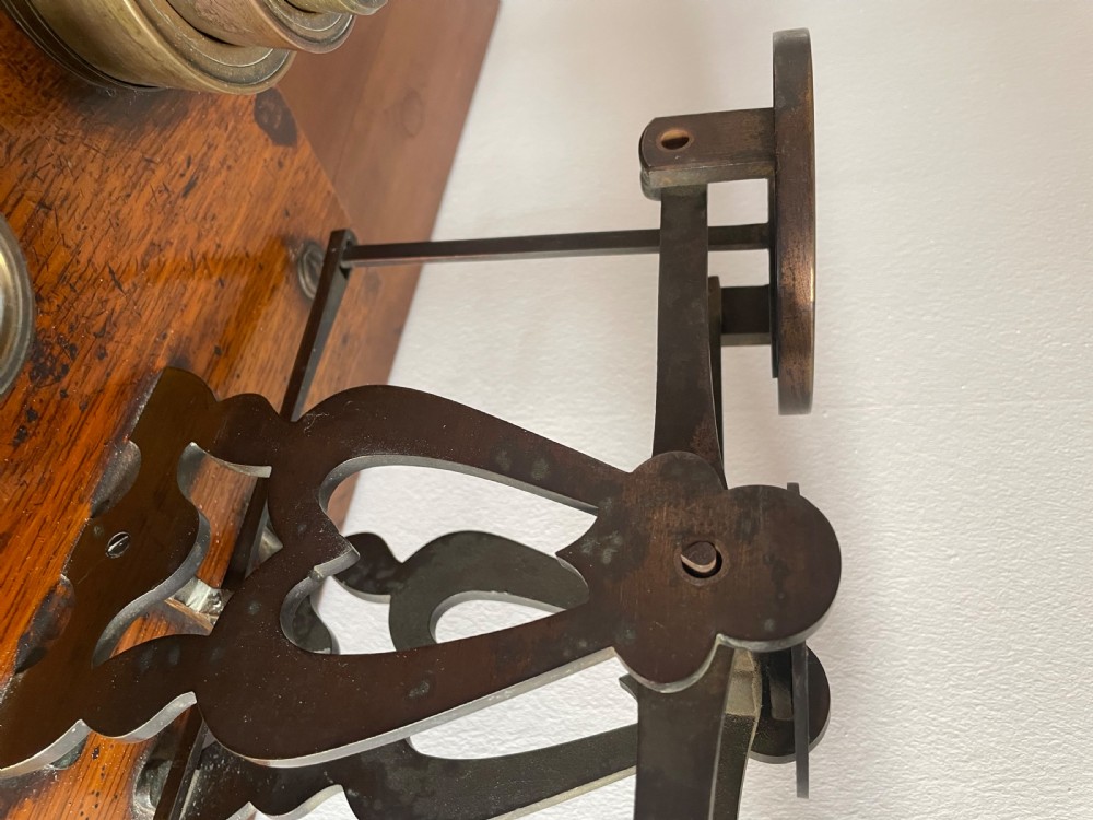 A set of Victorian brass postal scales mounted on a rectangular wooden base with nested brass weights stored in custom cutouts. View VI