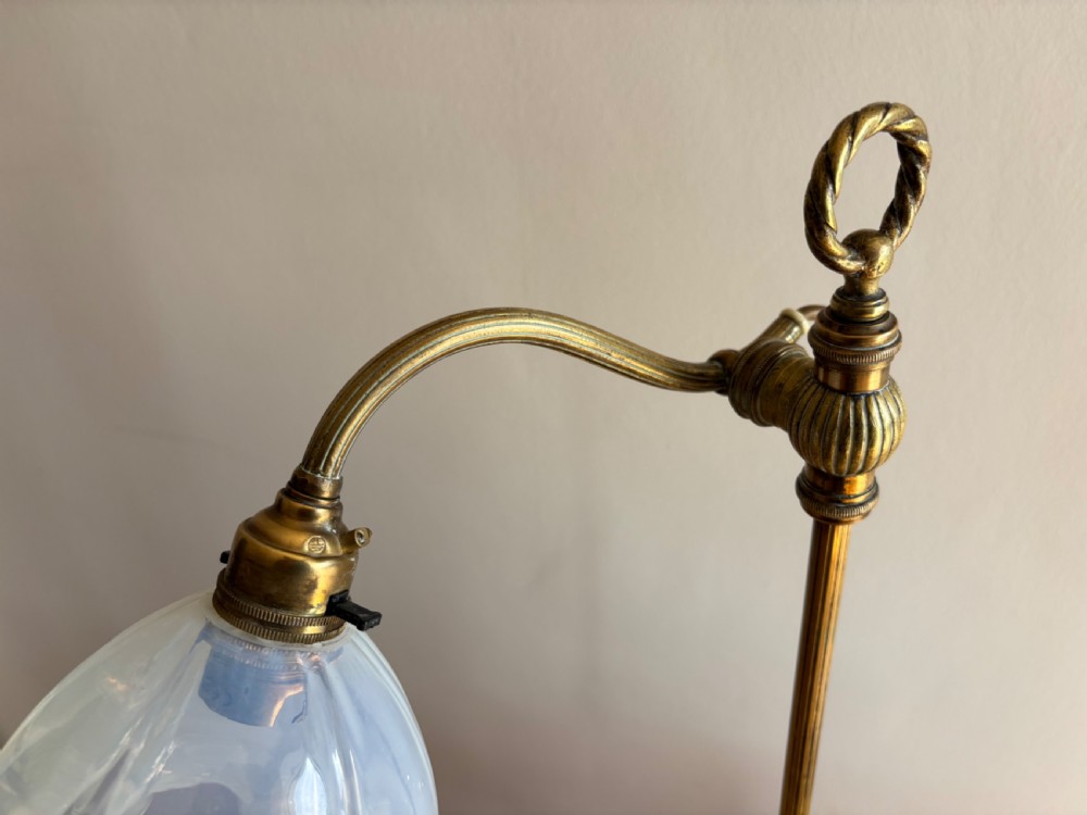 An Edwardian adjustable brass desk lamp featuring a circular stepped base, a vertical pole with a ring finial, a curved arm, and a translucent frilled glass shade. View II
