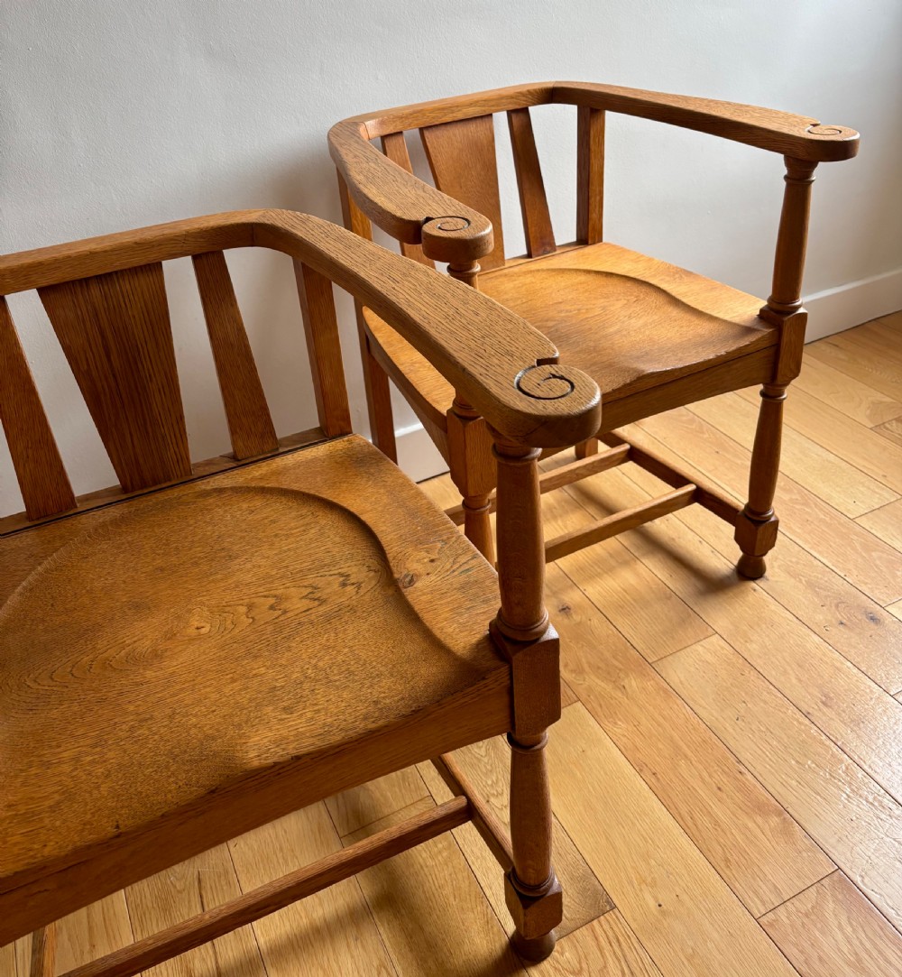 A pair of solid oak Edwardian armchairs featuring curved top rails, carved scroll handrests, vertical back splats, and contoured saddle seats. View II
