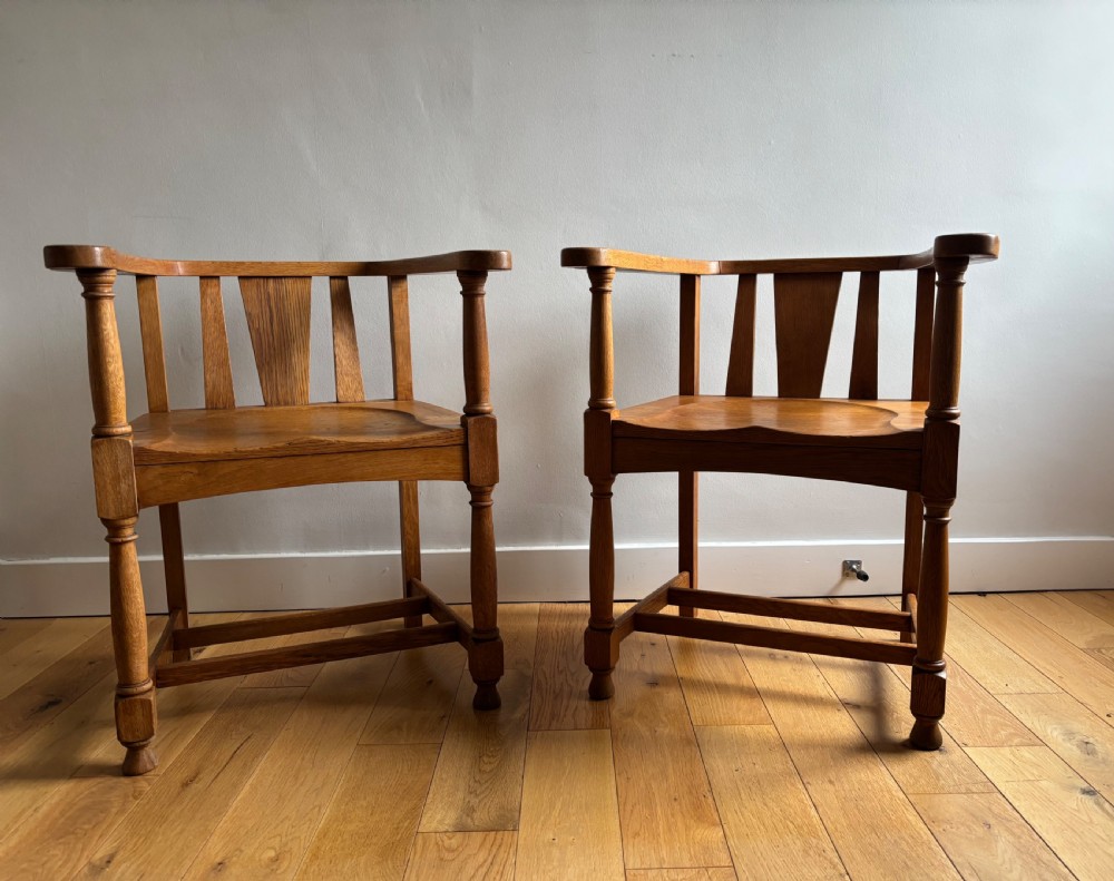 A pair of solid oak Edwardian armchairs featuring curved top rails, carved scroll handrests, vertical back splats, and contoured saddle seats. View IV