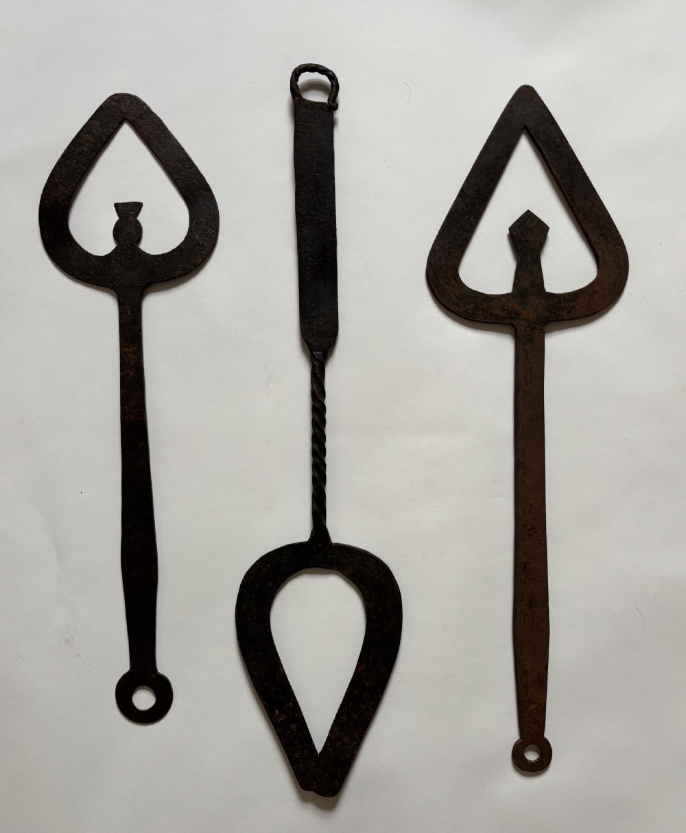 A set of seven hand-forged dark wrought iron Scottish bannock turners with decorative heart-shaped pierced blades and elongated handles. View III