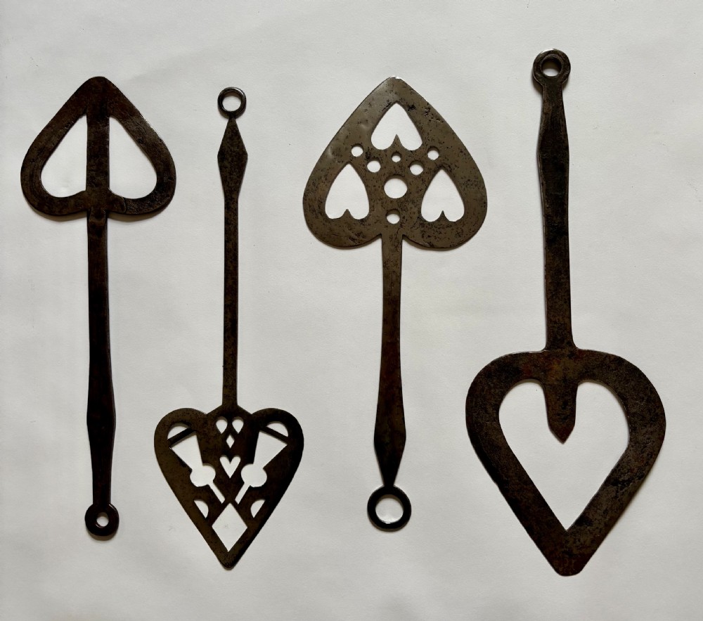 A set of seven hand-forged dark wrought iron Scottish bannock turners with decorative heart-shaped pierced blades and elongated handles. View IV