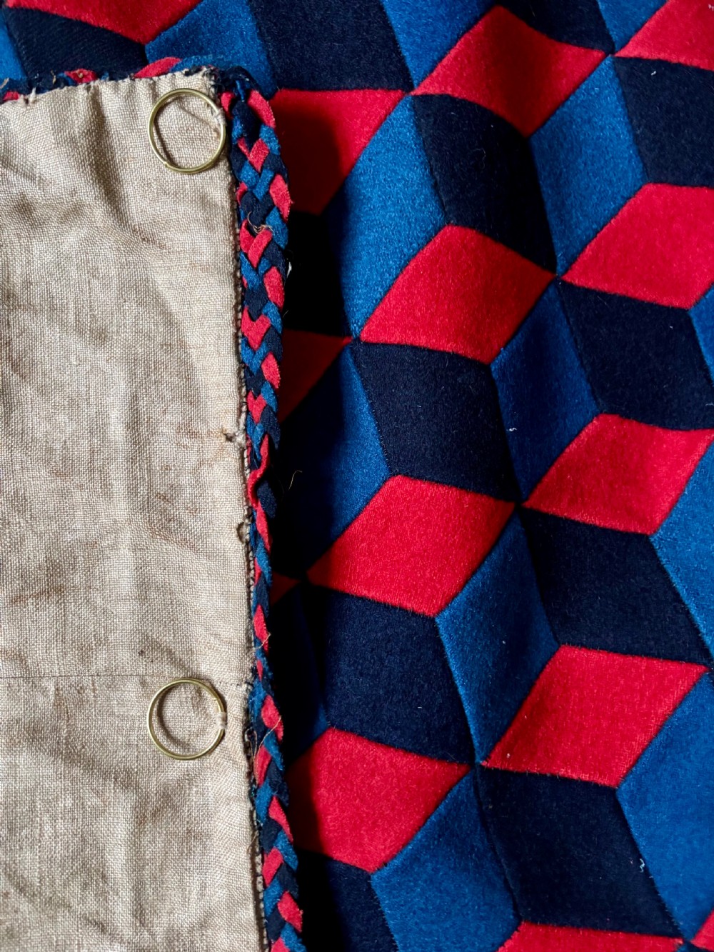 A rectangular Victorian patchwork textile featuring a repeating geometric tumbling blocks pattern in red, dark teal, and black fabric. View III