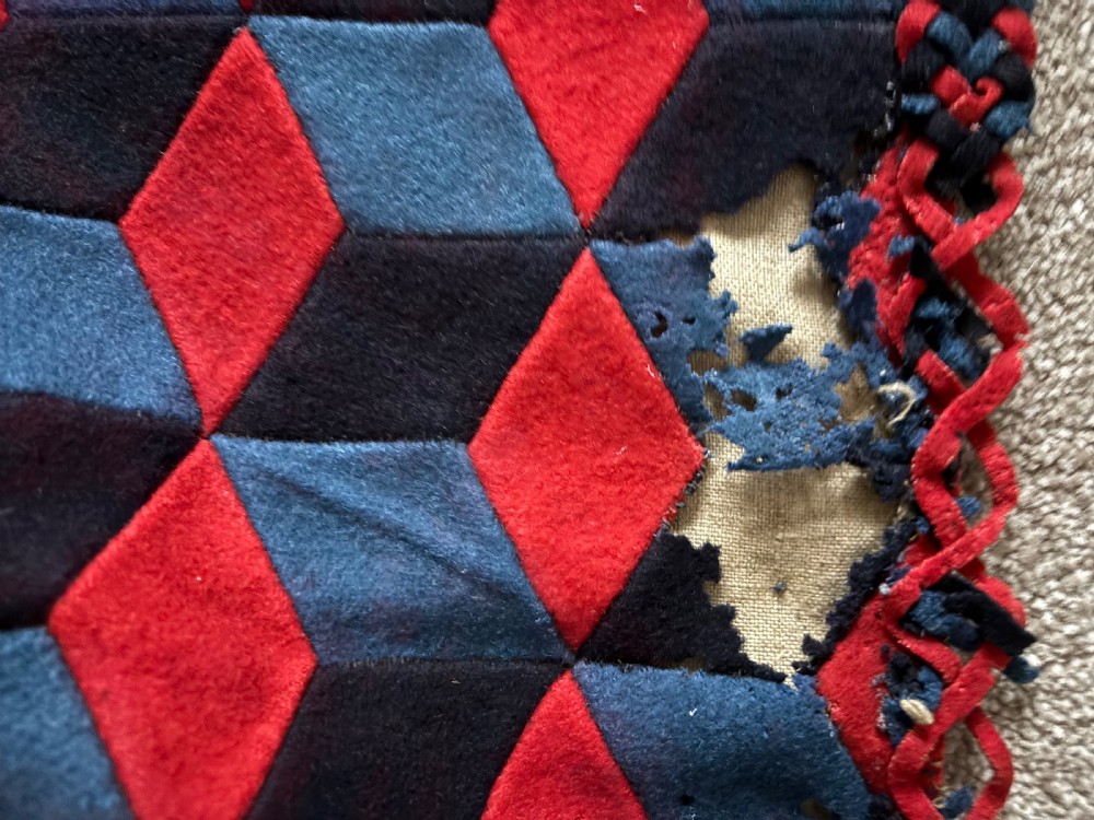 A rectangular Victorian patchwork textile featuring a repeating geometric tumbling blocks pattern in red, dark teal, and black fabric. View V