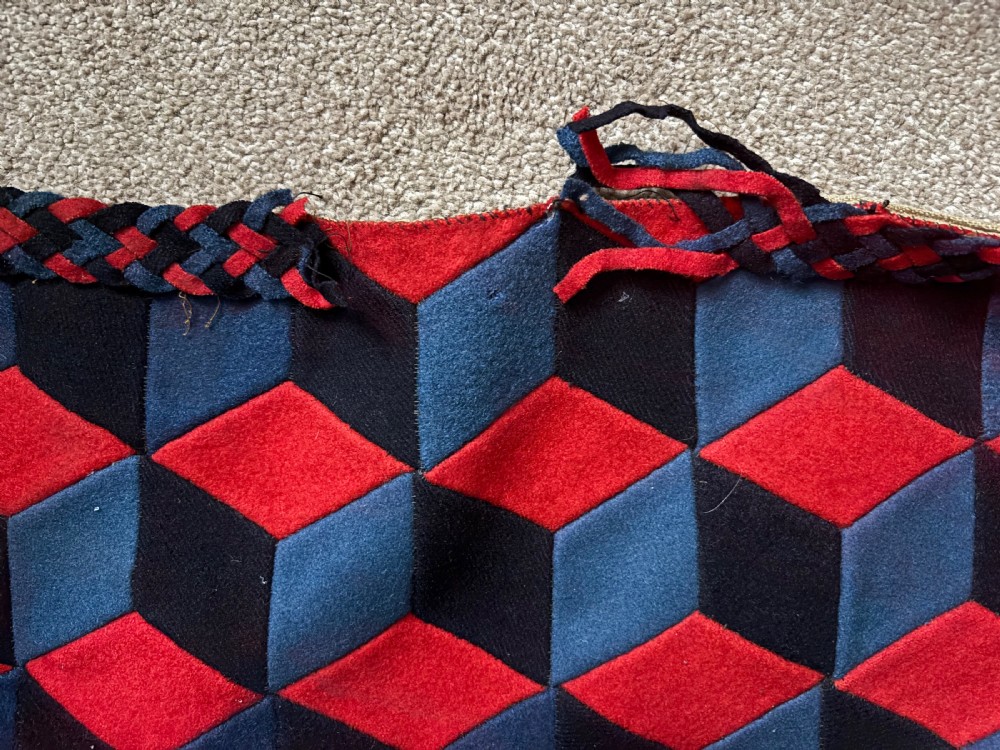 A rectangular Victorian patchwork textile featuring a repeating geometric tumbling blocks pattern in red, dark teal, and black fabric. View VII