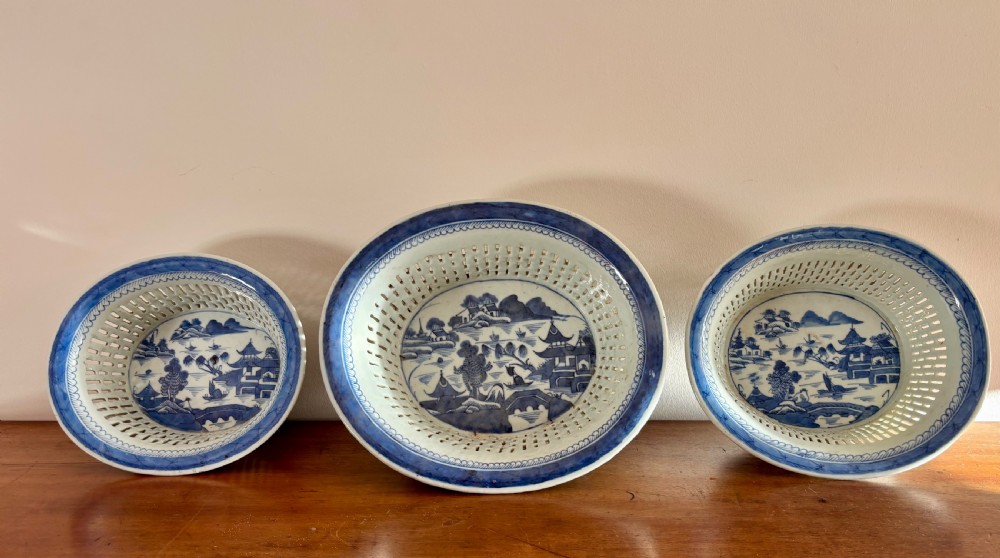 A set of three Chinese export blue and white porcelain reticulated baskets resting on matching pierced undertrays with hand-painted river landscape scenes. View II