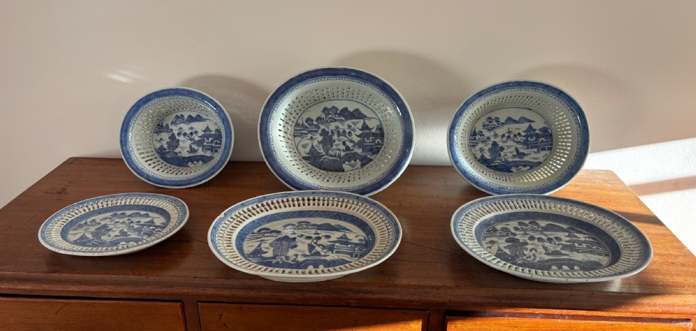 A set of three Chinese export blue and white porcelain reticulated baskets resting on matching pierced undertrays with hand-painted river landscape scenes. View V
