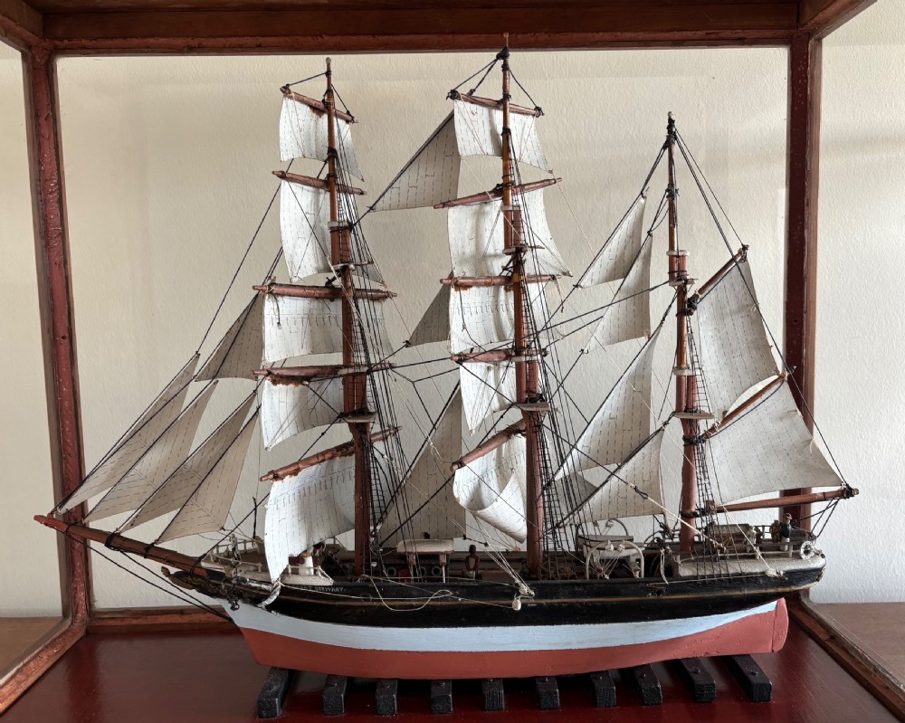 A detailed late Edwardian cased scale model of a three-masted barque sailing ship with full rigging, sails, and a painted hull.