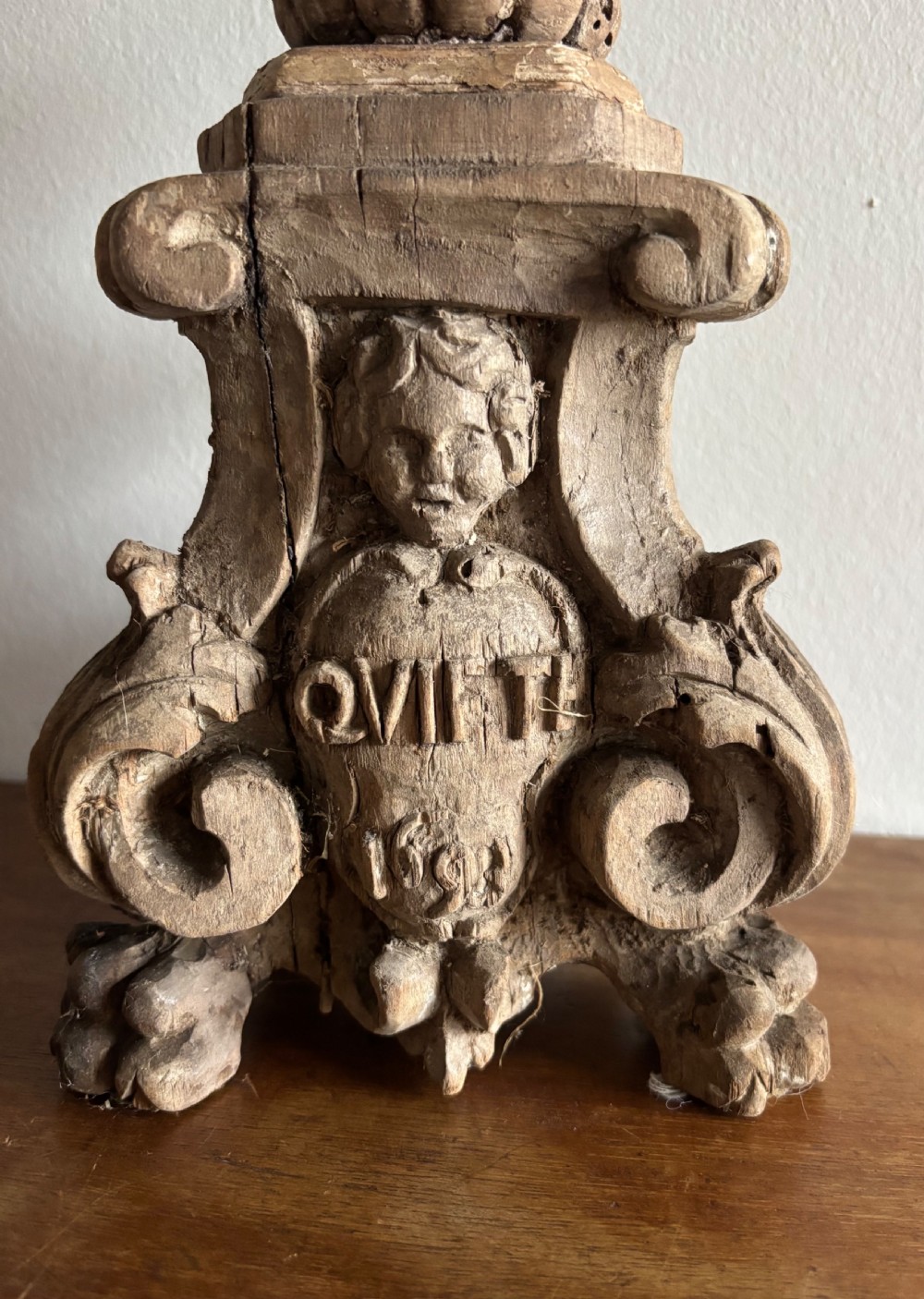 A tall 17th-century carved limewood candlestick featuring a scrollwork base with a carved cherub face, gadrooned stem, and dripan top. View II