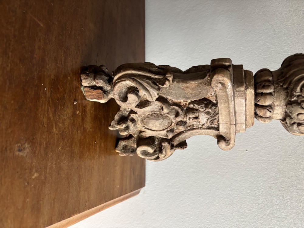 A tall 17th-century carved limewood candlestick featuring a scrollwork base with a carved cherub face, gadrooned stem, and dripan top. View III