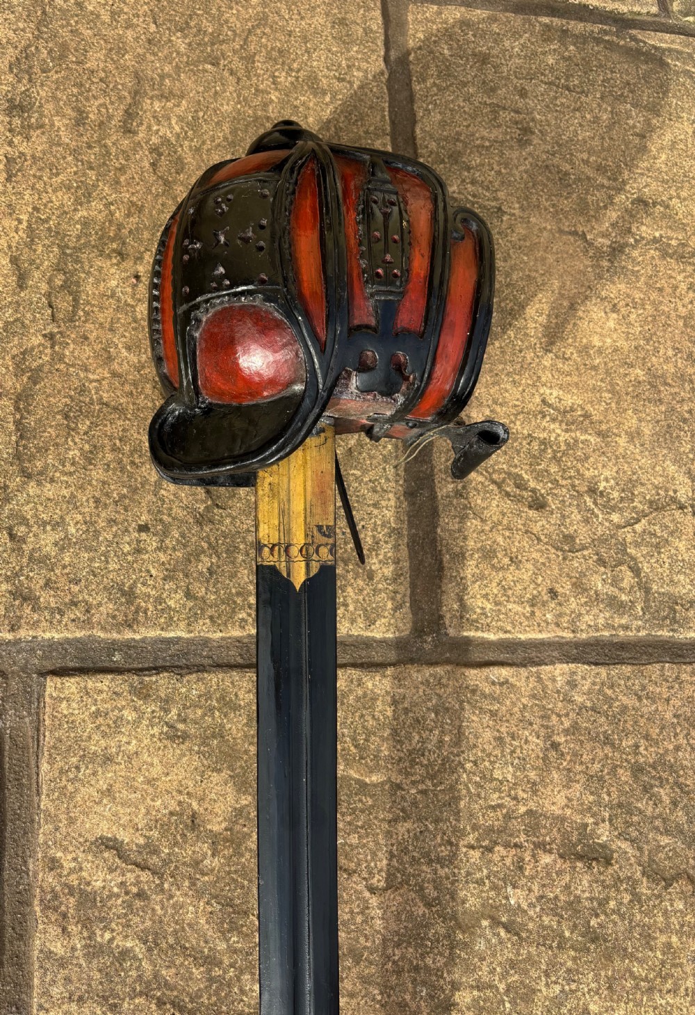 A Scottish wooden broadsword featuring a long dark blade and a basket guard lined with red leather. View III