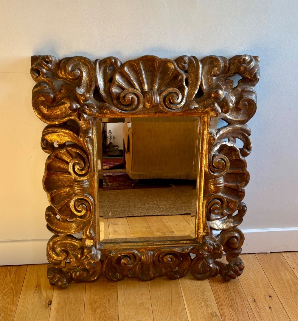 A rectangular mirror enclosed within a heavily carved giltwood frame featuring elaborate scrollwork and shell motifs. View II