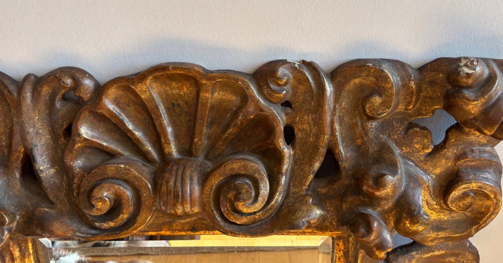 A rectangular mirror enclosed within a heavily carved giltwood frame featuring elaborate scrollwork and shell motifs. View IV