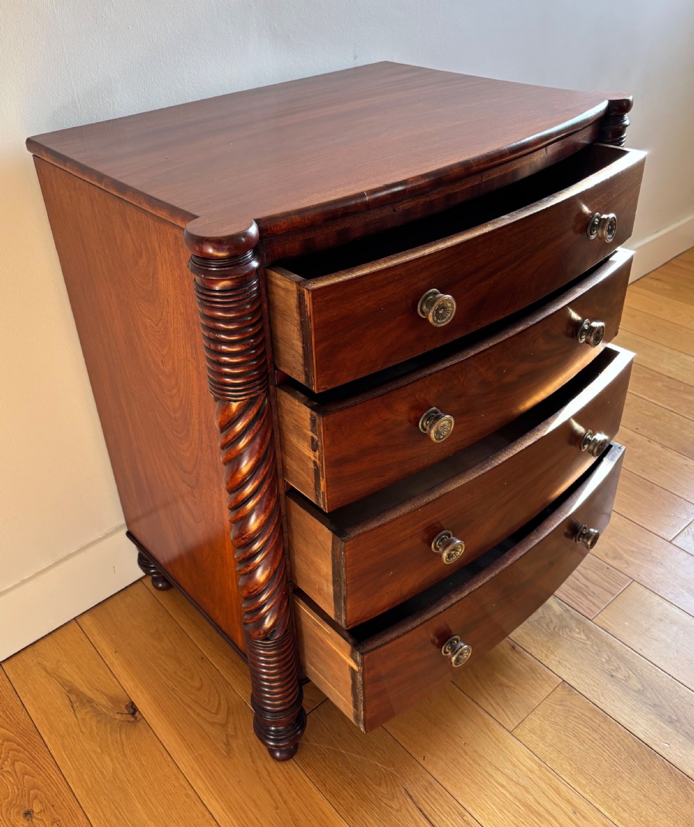 A small William IV mahogany bowfront chest of four drawers flanked by carved spiral-twist side columns and supported on turned feet. View IV