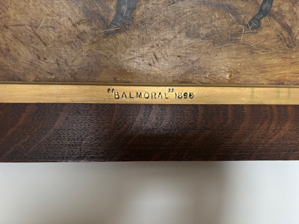 A late Victorian equestrian oil painting depicting a dark horse titled Balmoral in a stable setting, presented within a wide oak frame with a gilt inner slip. View IV