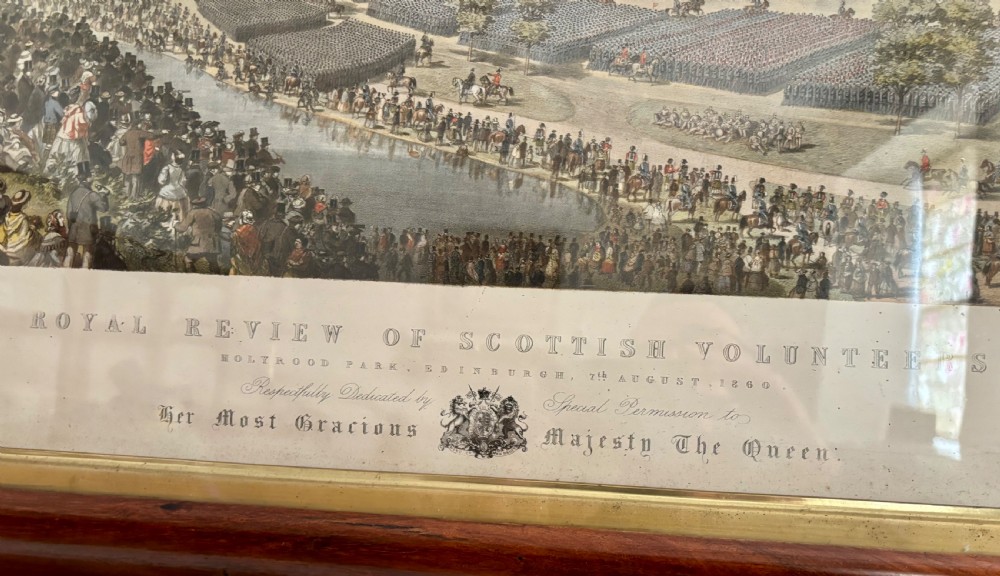 A framed Victorian military print depicting a panoramic view of the Royal Review of the Scottish Volunteers in a dark wooden frame with a gold slip. View III