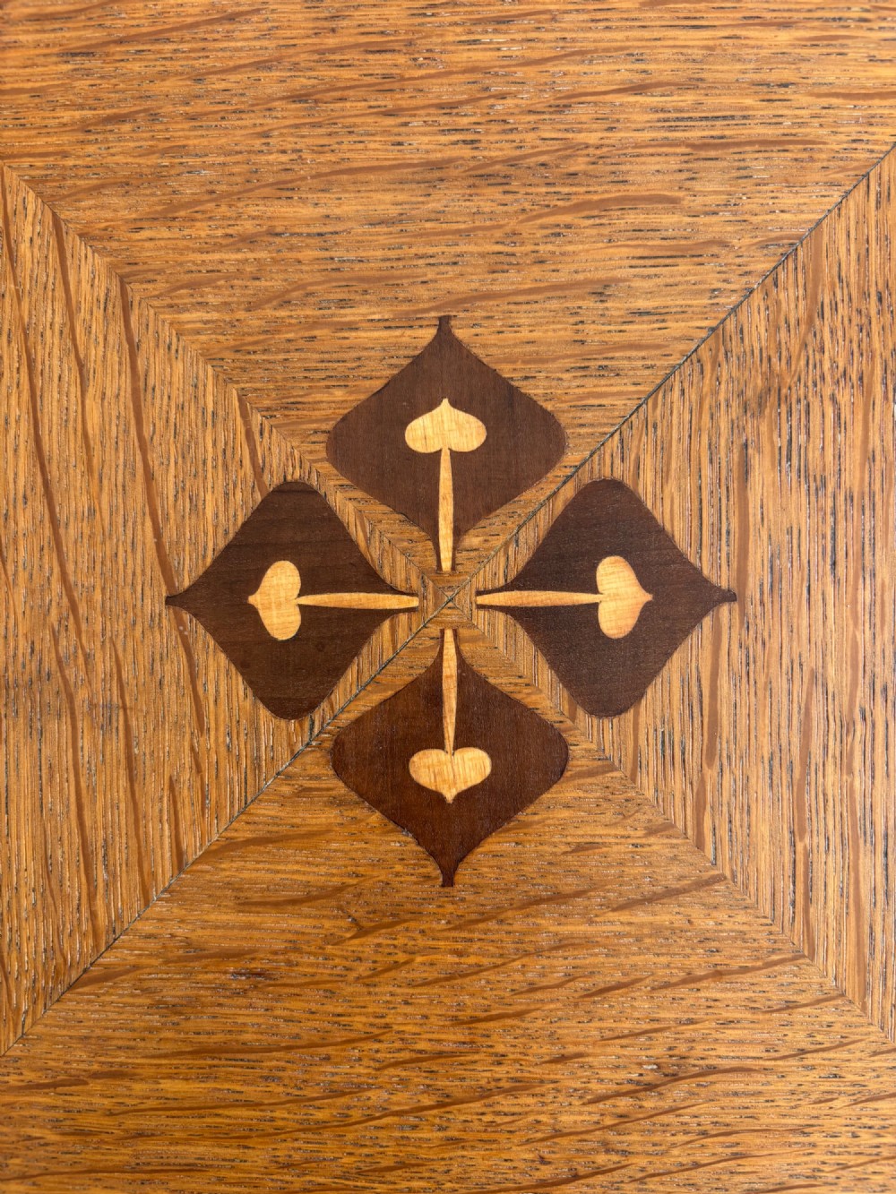 An antique Arts and Crafts square oak occasional table featuring a central marquetry motif, banded inlay border, lower tier shelf, and straight legs. View II