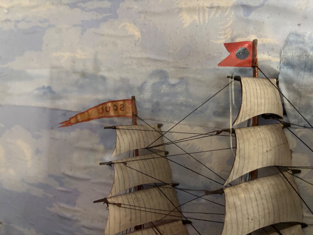 A Victorian glazed shadow box diorama depicting a three-masted clipper ship in full sail alongside a smaller vessel and lighthouse, framed in a polished wooden frame with a gilt slip. View II