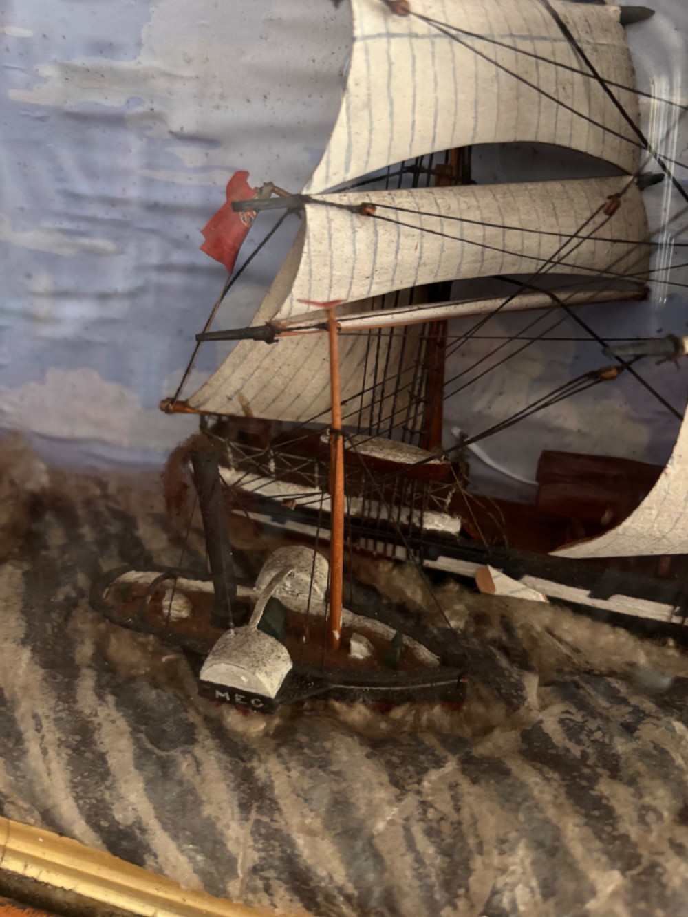 A Victorian glazed shadow box diorama depicting a three-masted clipper ship in full sail alongside a smaller vessel and lighthouse, framed in a polished wooden frame with a gilt slip. View III
