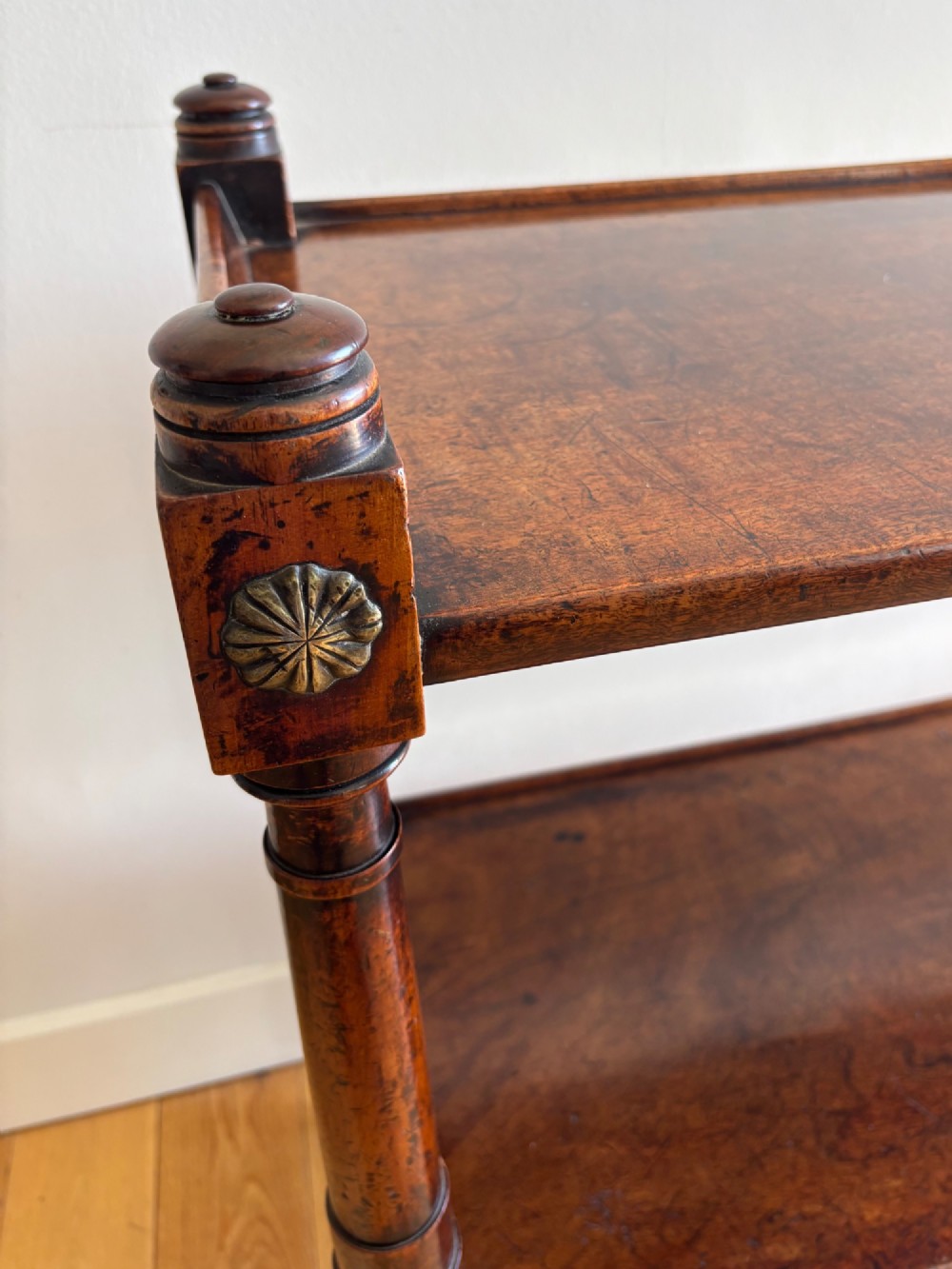 A two-tier mahogany Regency whatnot featuring turned upright supports, carved rosette details on corner blocks, top finials, and brass castors. View II