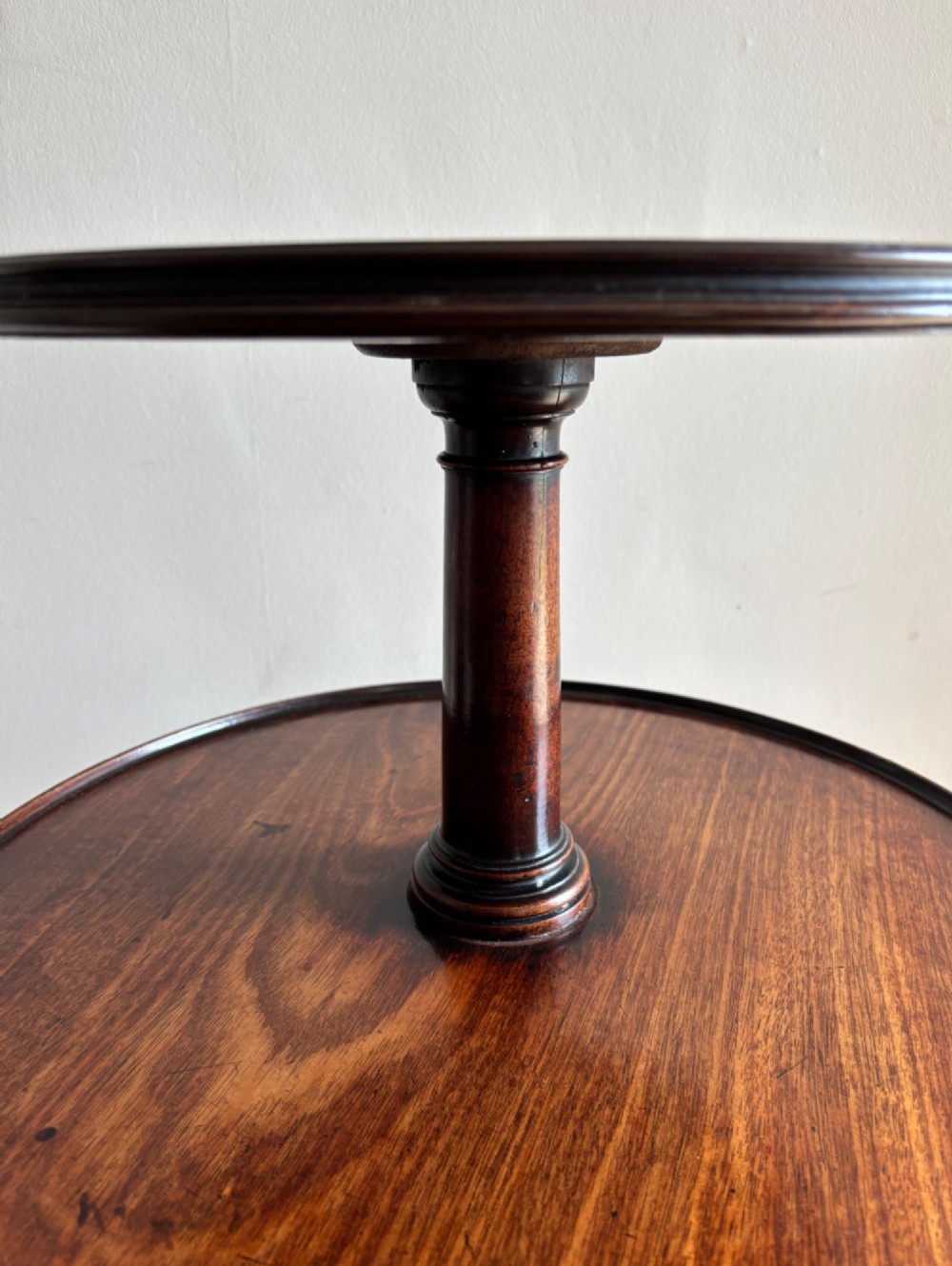 An early George III mahogany dumb waiter featuring three graduated circular trays on a turned central column supported by a tripod base with pad feet. View III