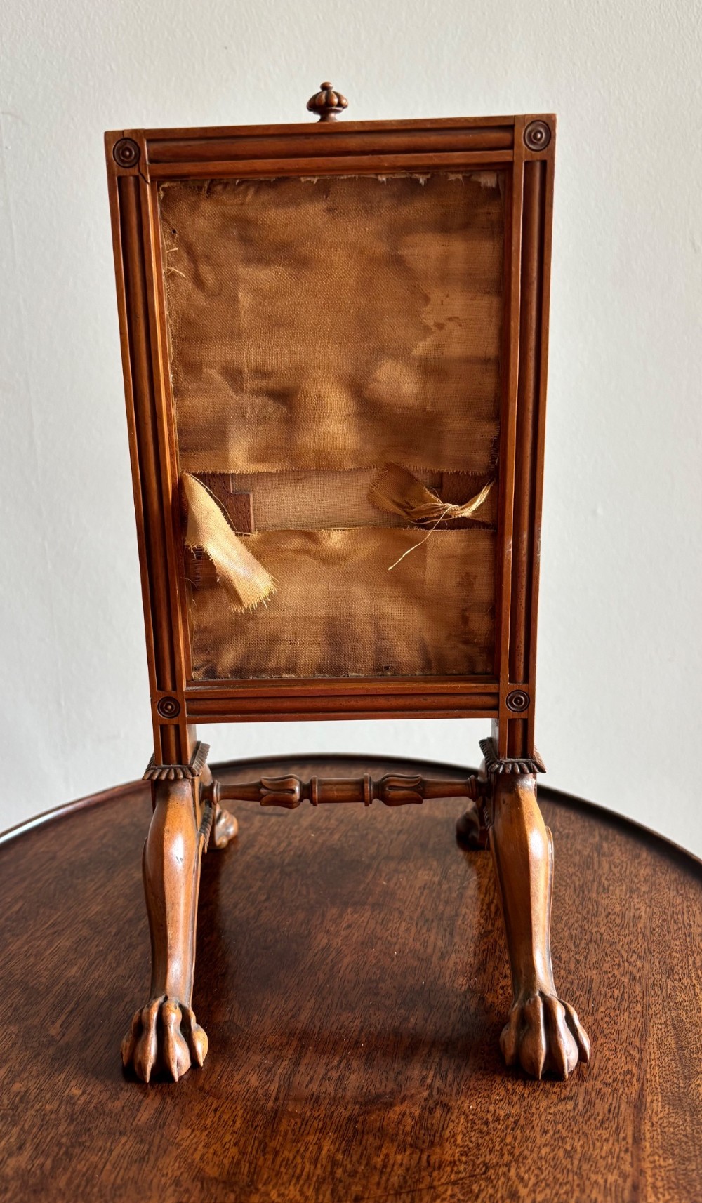 An antique Regency miniature mahogany fire screen featuring a carved frame, claw feet, and a central floral needlepoint textile panel. View V