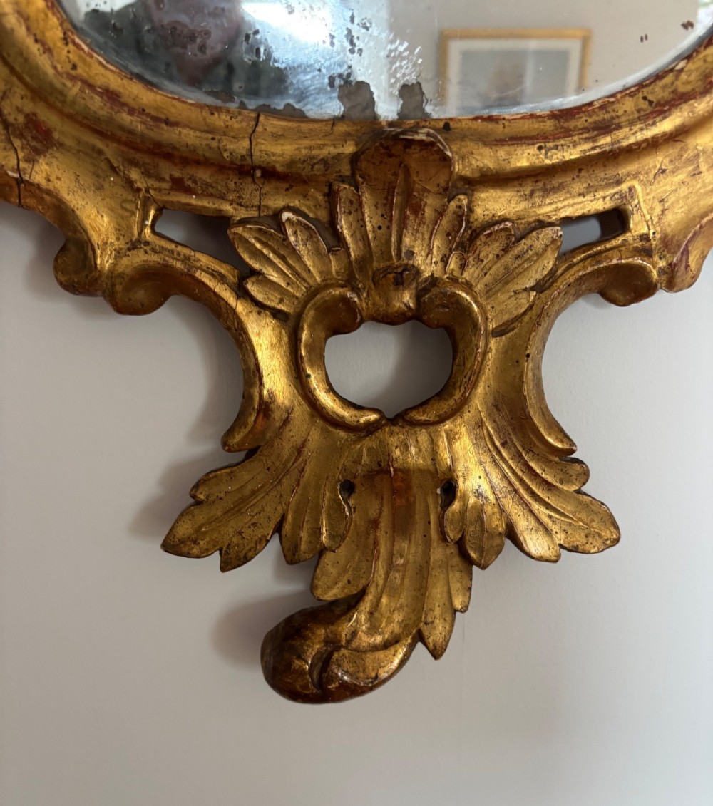 A pair of carved 18th century Venetian giltwood wall mirrors with crests featuring flower baskets and bird motifs flanking the frames. View III