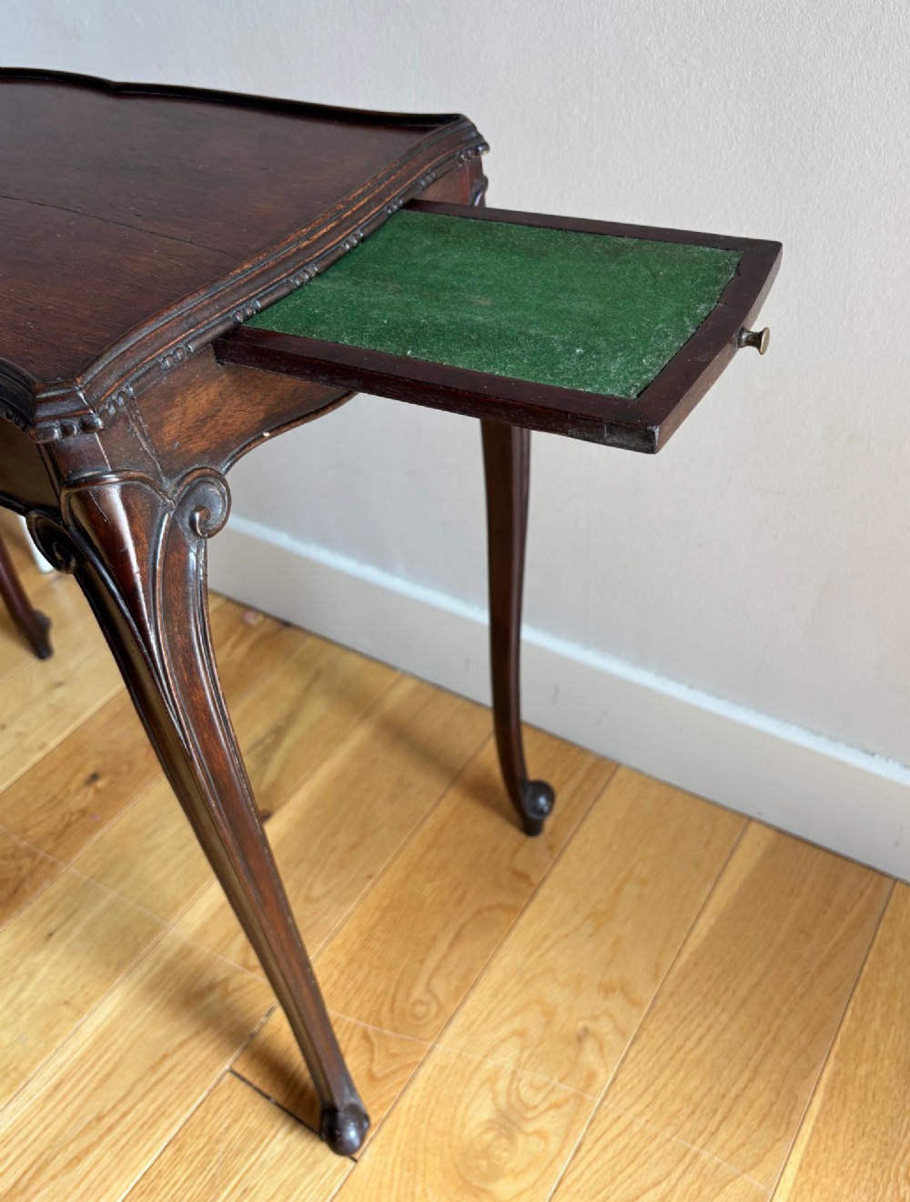An Edwardian mahogany occasional table with a serpentine top, carved frieze, and slender cabriole legs. View III