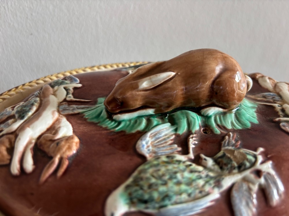 An oval brown glazed Victorian Wedgwood game pie dish decorated with green relief grapevines, hanging game birds, and a resting hare finial on the lid. View II