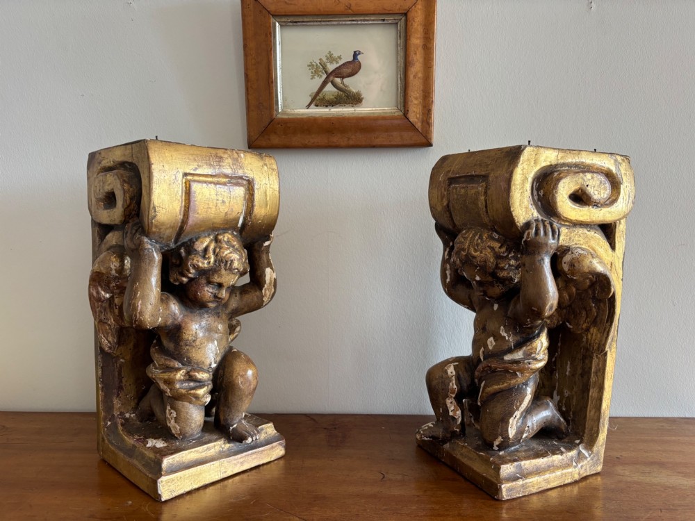 A pair of 19th-century carved giltwood wall brackets featuring winged cherub figures supporting scrolled capitals. View II