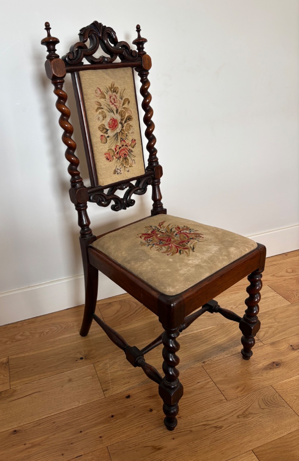 A Victorian rosewood childs chair with barley twist uprights, floral scrollwork carvings, and floral needlepoint upholstery on the seat and backrest.