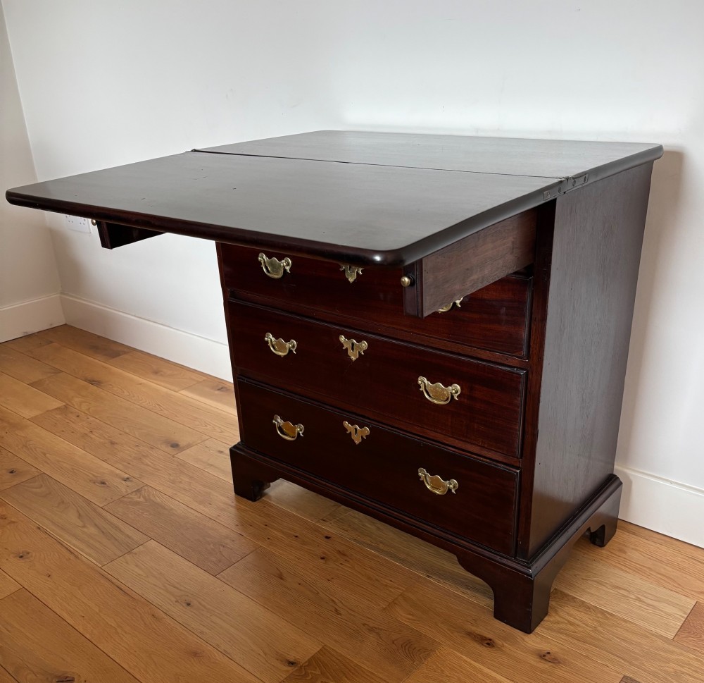 A George III mahogany bachelors chest featuring four graduated drawers with brass handles, a folding top, and bracket feet. View III