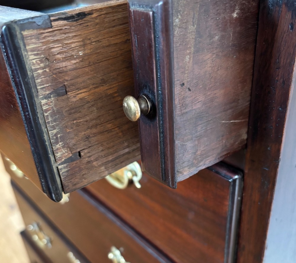 A George III mahogany bachelors chest featuring four graduated drawers with brass handles, a folding top, and bracket feet. View IV
