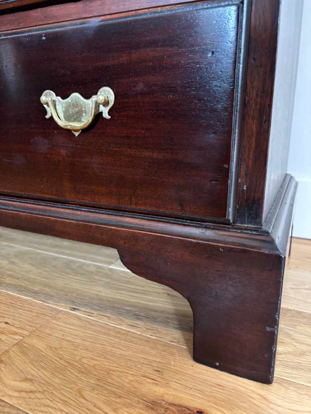 A George III mahogany bachelors chest featuring four graduated drawers with brass handles, a folding top, and bracket feet. View V