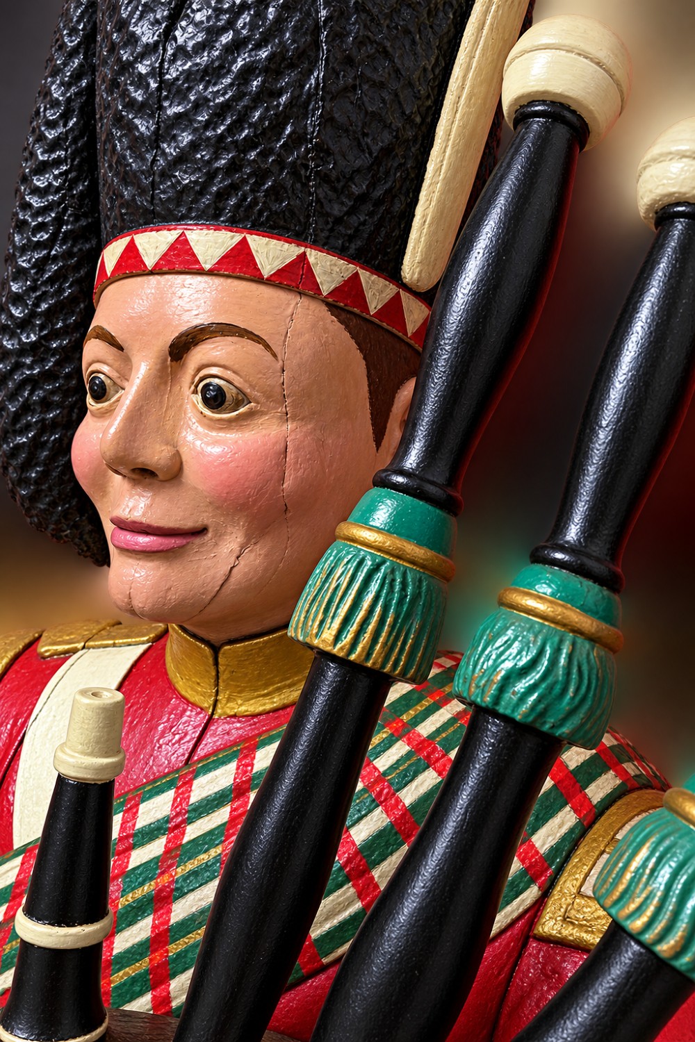 A nineteenth-century polychrome carved wooden figure of a Highland bagpiper in traditional dress seated on a wooden barrel. View III