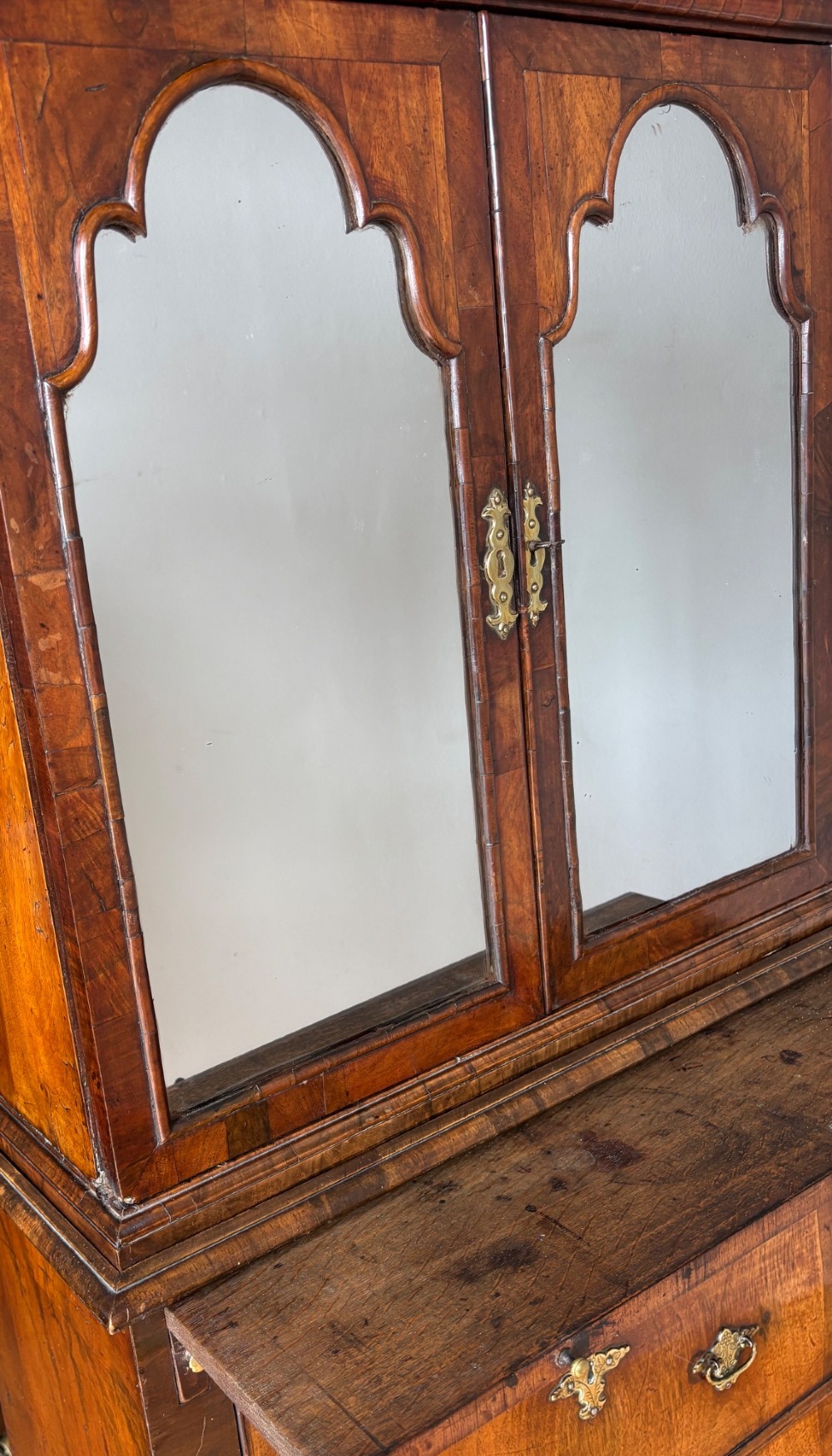 An eighteenth-century George II walnut cabinet on chest featuring arched door panels above drawers with brass handles and bracket feet. View III