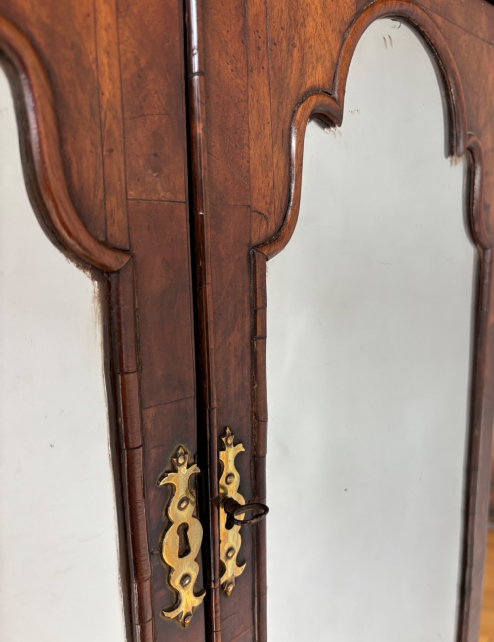 An eighteenth-century George II walnut cabinet on chest featuring arched door panels above drawers with brass handles and bracket feet. View IV
