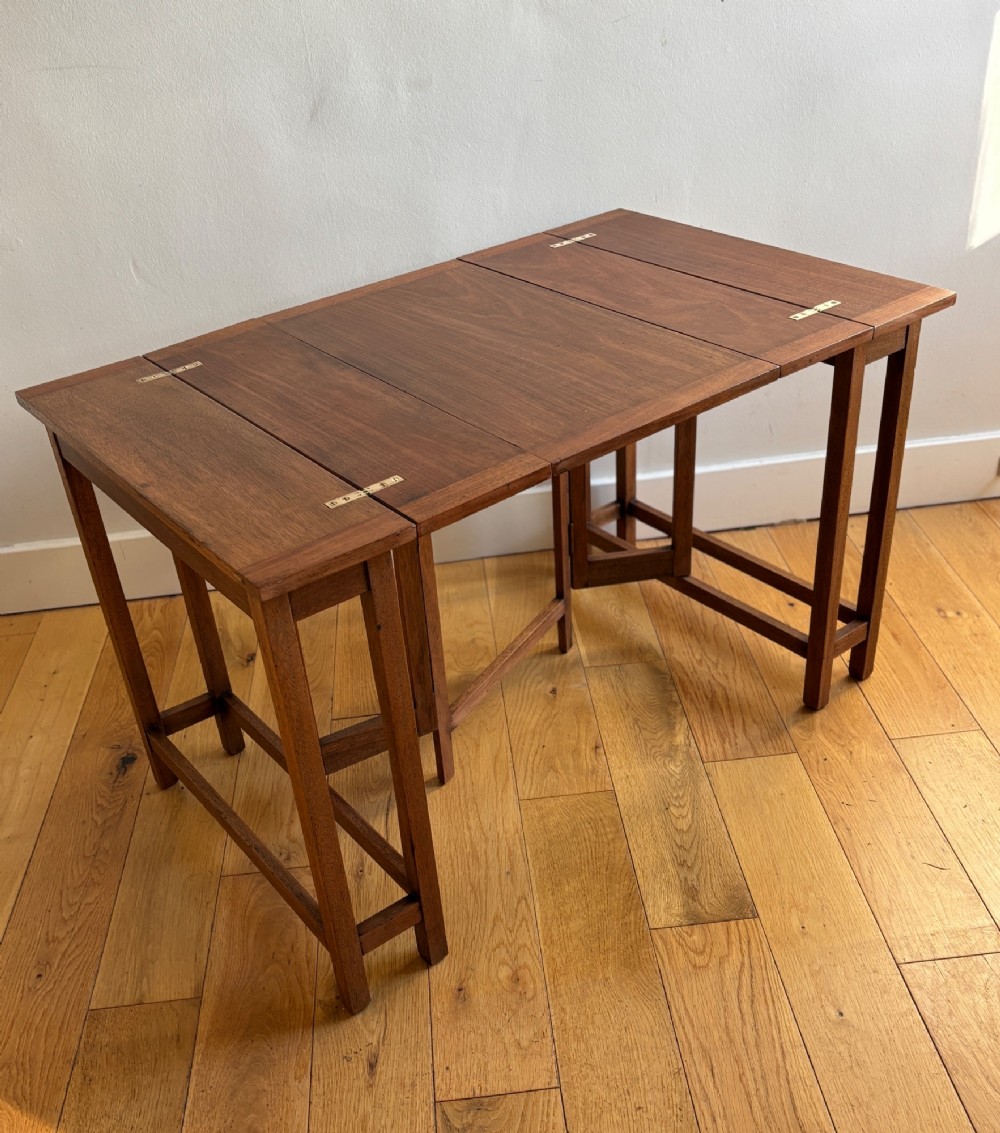 A rectangular mahogany folding table with visible brass hinges and a foldable timber leg support structure.