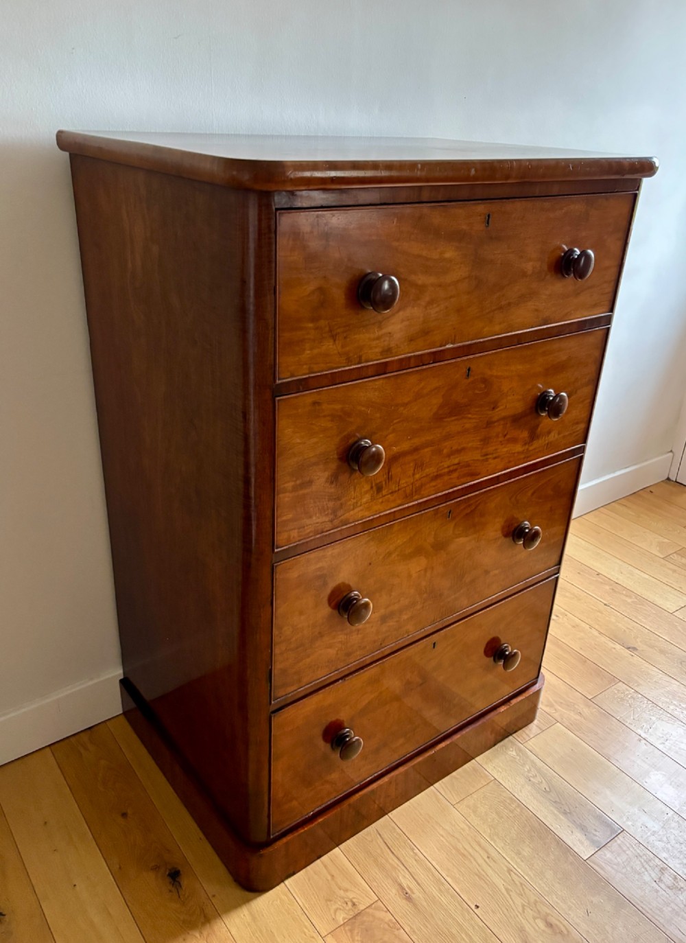 A mid-Victorian mahogany chest of drawers featuring four full-width drawers with turned wooden knobs set on a continuous plinth base.