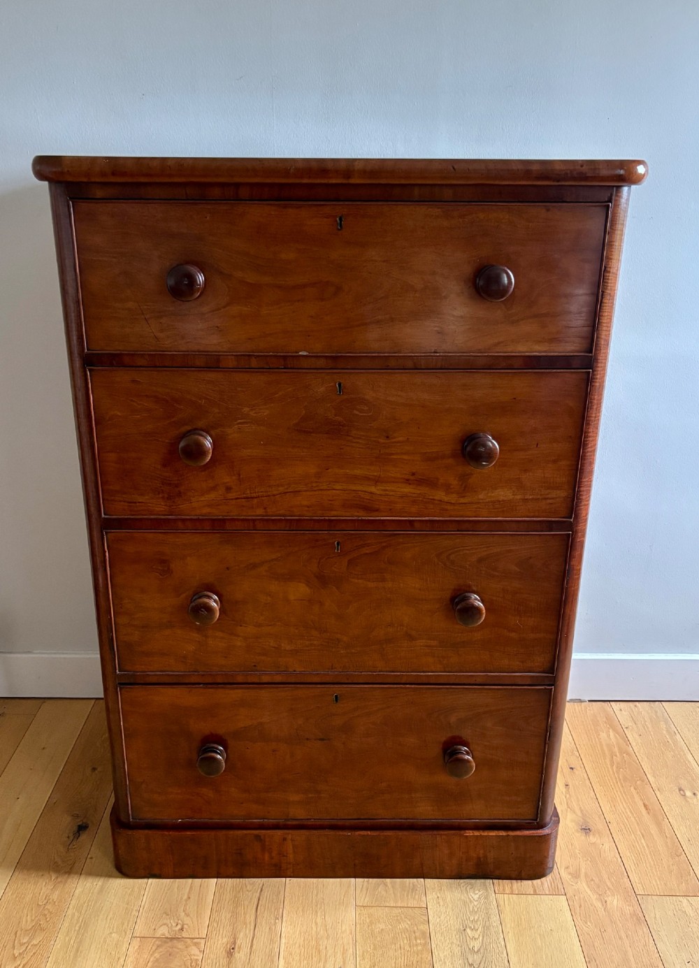 A mid-Victorian mahogany chest of drawers featuring four full-width drawers with turned wooden knobs set on a continuous plinth base. View II