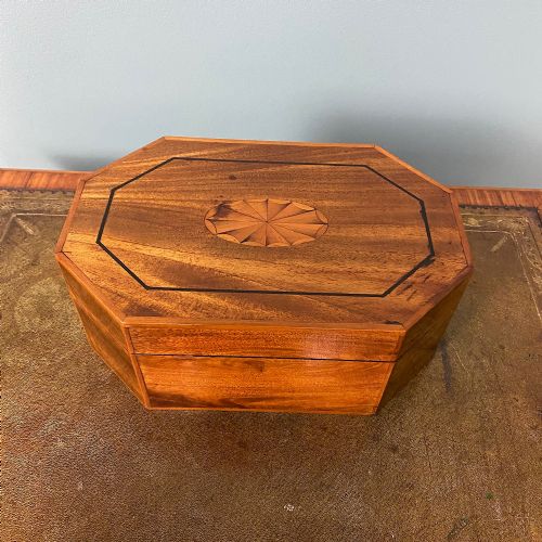 fig 1. An octagonal Victorian warm brown wooden box featuring a central starburst wood inlay on the hinged lid.