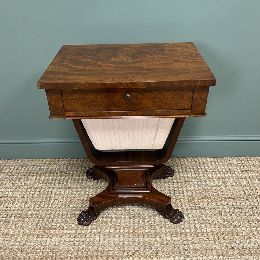 A William IV flame mahogany work table featuring a top drawer, pleated fabric work basket, U-shaped pedestal support, and carved claw feet. View V