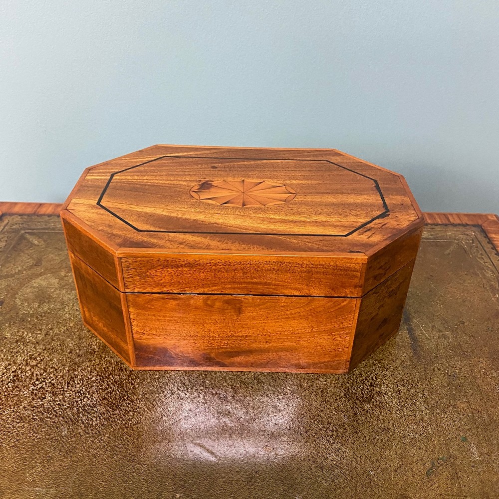 An octagonal Victorian warm brown wooden box featuring a central starburst wood inlay on the hinged lid.