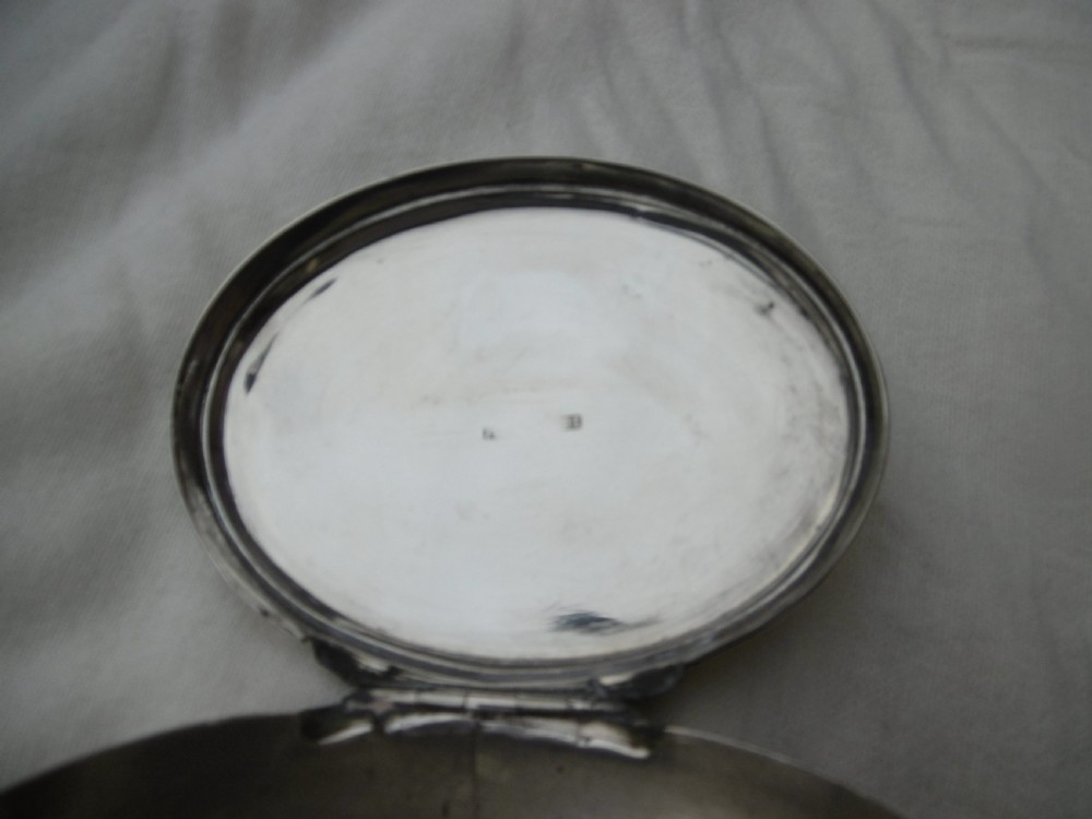 An 18th-century oval sterling silver box featuring a hinged lid engraved with a family crest depicting an arm holding a scimitar. View II