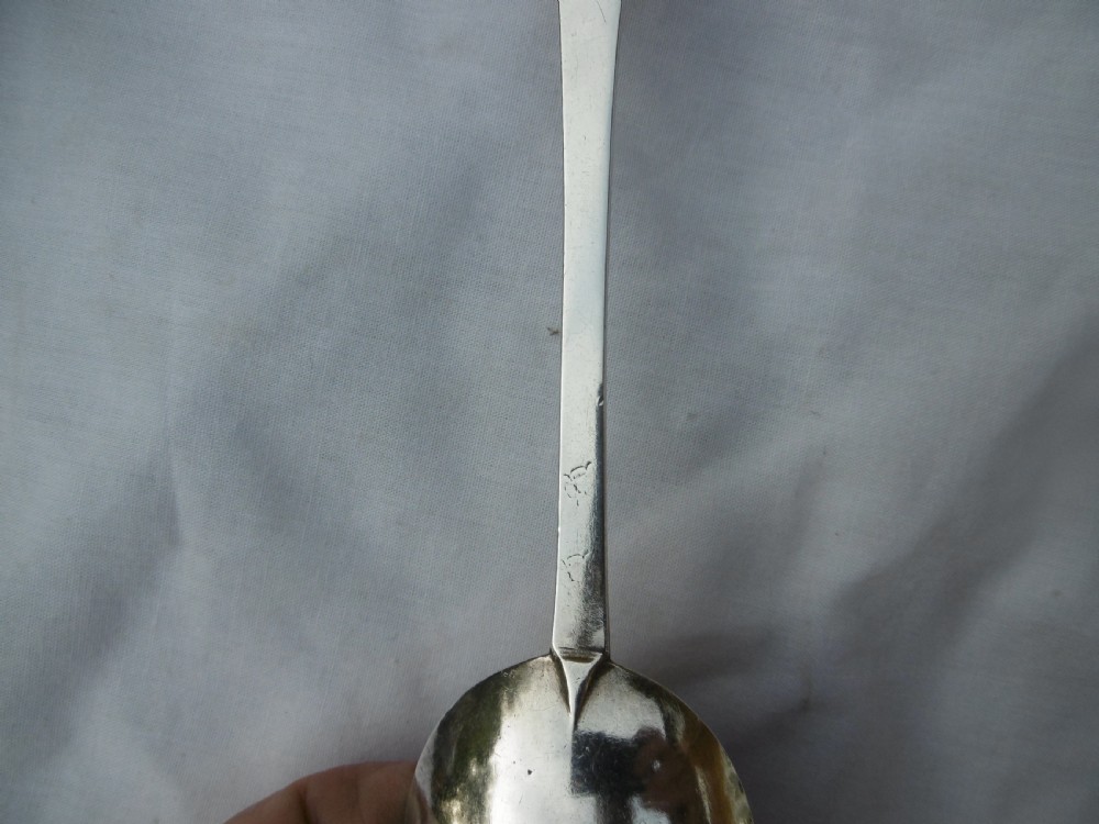 An antique silver trefid spoon featuring a notched three-lobed handle end with hand-engraved initials and an oval bowl. View II