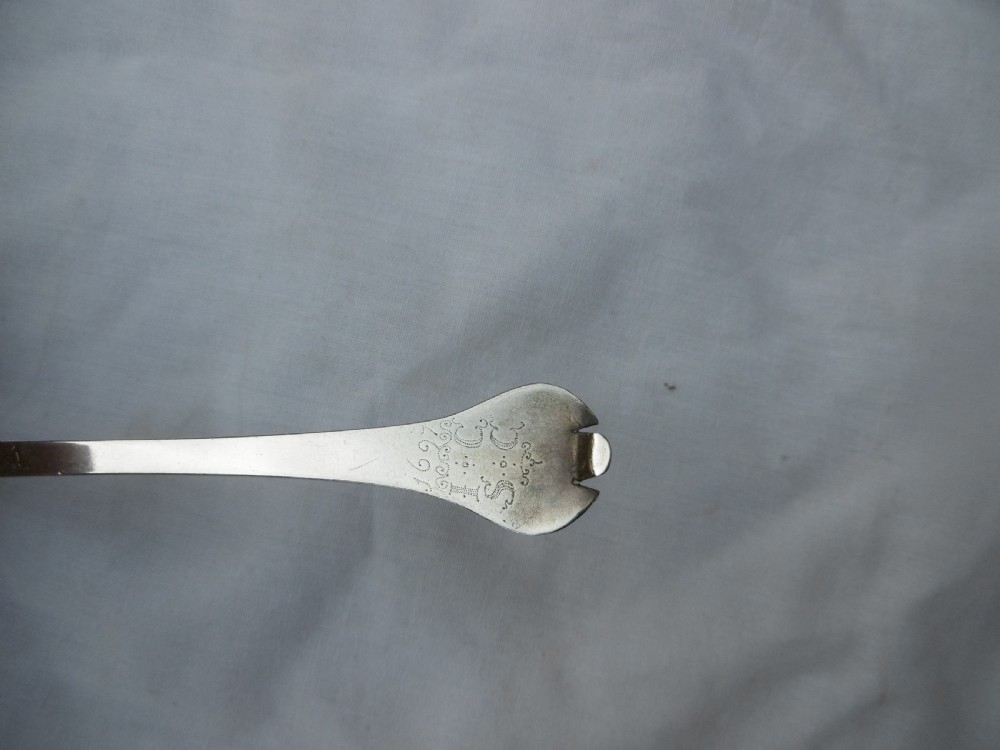 An antique silver trefid spoon featuring a notched three-lobed handle end with hand-engraved initials and an oval bowl. View III