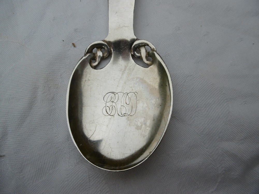 An Edwardian sterling silver spoon featuring stylised Celtic knotwork at the handle terminal and junction, with an engraved monogram inside the oval bowl. View IV