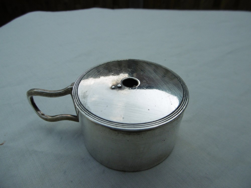 A small cylindrical Georgian sterling silver bougie box with a side loop handle and a circular hole in the lid.