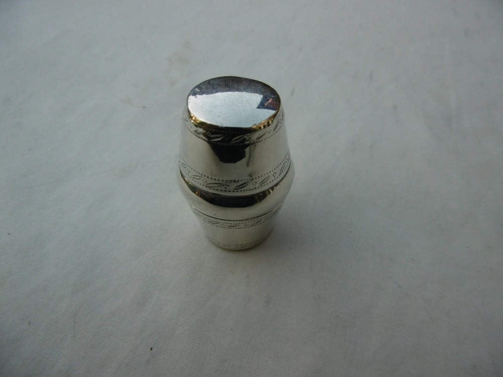 An antique Georgian sterling silver barrel-shaped nutmeg grater shown unscrewed into three component parts including cap, grater plate, and main body. View II