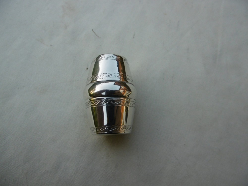 An antique Georgian sterling silver barrel-shaped nutmeg grater shown unscrewed into three component parts including cap, grater plate, and main body. View III